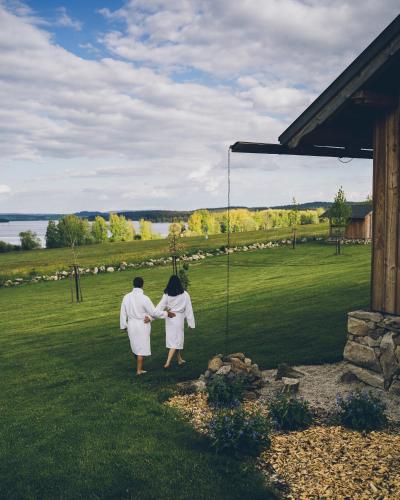 two people in white robes walking in the grass at Aparthotel & Wellness Knížecí cesta in Horní Planá