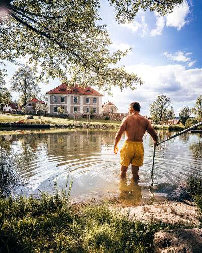 a man standing in the water holding a fishing pole at Aparthotel & Wellness Knížecí cesta in Horní Planá