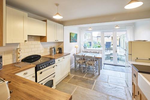 a kitchen with white cabinets and a table with a dining room at Host & Stay - Willow Cottage in Helmsley