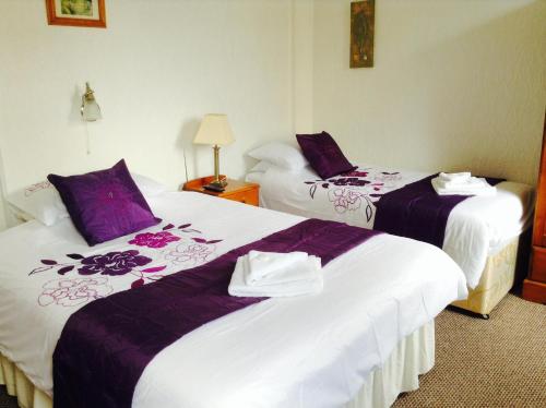 ブラックプールにあるLegends Hotelの紫と白のシーツが備わるホテルルームのベッド2台