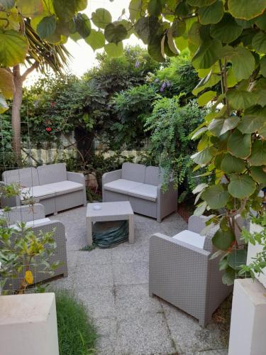 un patio con divani, tavolo e piante di Rooms Project B&B a Capoterra