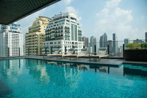 a swimming pool with chairs and a city skyline at Sukhumvit 11#Luxury#Pool#Gym#BTS Nana&MRT Sukhumvit#1BR#Max4ppl in Bangkok