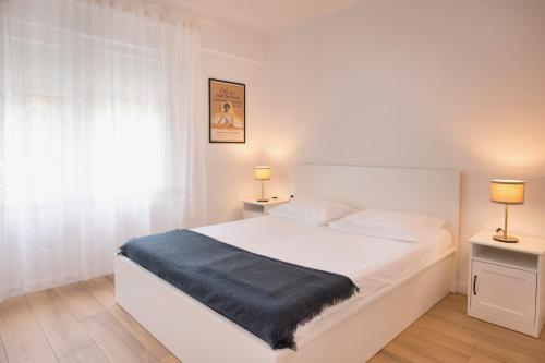 a bedroom with a large white bed with two lamps at Firpo - Cozy two bedroom city centre apartment in Vis