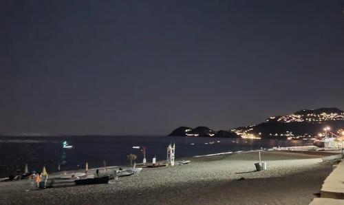 a beach at night with lights on the water at Casa Macallè - Letojanni - Taormina in Letojanni