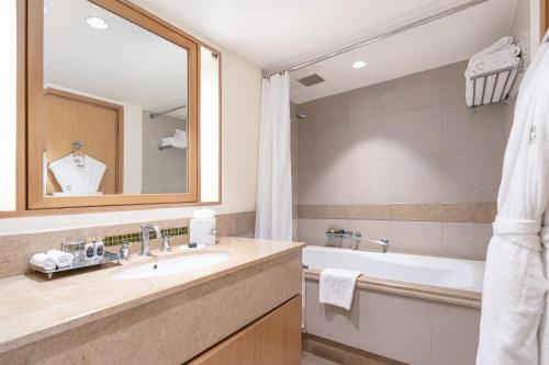 a bathroom with a sink and a tub and a mirror at Taj Wellington Mews, Mumbai in Mumbai