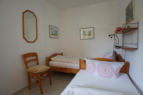a bedroom with two beds and a chair and a mirror at Oland Whg 12 Lachmöwe in Wyk auf Föhr