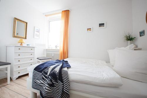 biała sypialnia z łóżkiem, komodą i oknem w obiekcie Haus Uthlande Uthlande Whg 32 Sonnendeck w mieście Wyk auf Föhr