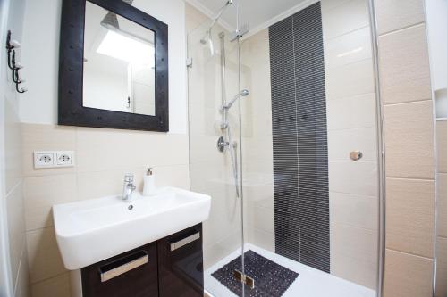ein Bad mit einem Waschbecken und einer Dusche mit einem Spiegel in der Unterkunft Haus Uthlande Uthlande Whg 52 Möwennest in Wyk auf Föhr