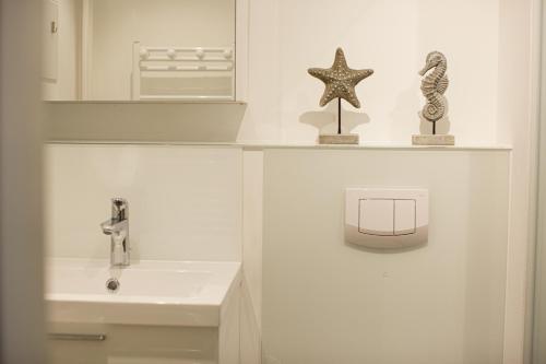 La salle de bains est pourvue d'un lavabo et d'une étoile de mer sur une étagère. dans l'établissement Haus Uthlande Uthlande Whg 11 Strandglück, à Wyk auf Föhr
