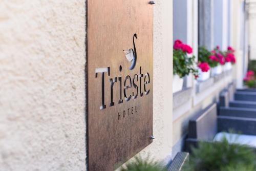 a sign on the side of a building with flowers at Hotel Trieste in Morbegno