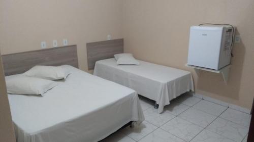 a room with two beds and a tv on the wall at Porto Seguro Hotel - Porto Velho in Porto Velho