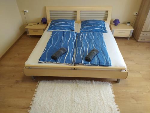 バラトンケレストゥールにあるBerni Apartmanのベッド(青い掛け布団、靴付)