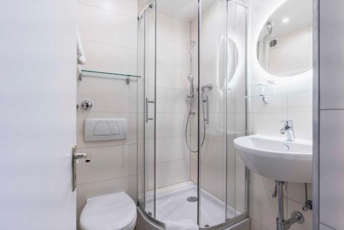 a bathroom with a shower and a toilet and a sink at Westend Hotel (non-smoking) in Munich