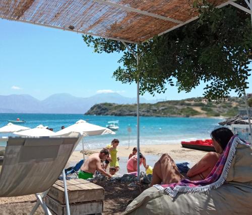 
people sitting on a beach with umbrellas at Faedra Beach Resort in Agios Nikolaos
