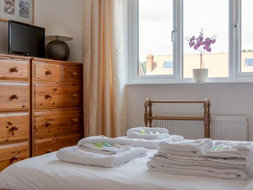 łóżko z ręcznikami, komodą i oknem w obiekcie Pass the Keys Cheerful 2-Bedroom house with Private parking w mieście Canterbury