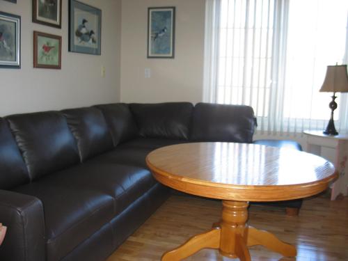 a living room with a black leather couch and a wooden table at Arnica Bed & Breakfast in Niagara on the Lake