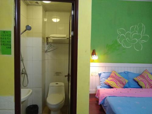 a bathroom with a bed and a toilet and a sink at Yangshuo How Flowers Hostel in Yangshuo