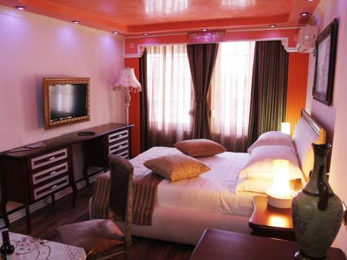a bedroom with a bed and a desk and a television at Hotel Boutique Vila Fernando Tirana in Tirana