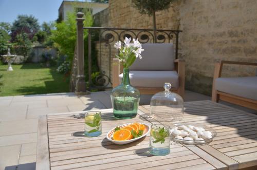a table with a vase of flowers and a bowl of oranges at Chambres d'hôtes - La Maison 19 in Niort