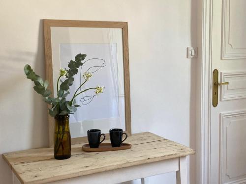a vase with flowers on a table in front of a mirror at Chambres d'hôtes - La Maison 19 in Niort