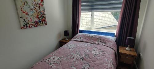 a small bedroom with a pink bed and a window at Golden Plover at Plover Cottage Lindley in Huddersfield