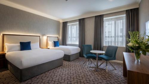 a hotel room with two beds and a table and chairs at Eyre Square Hotel in Galway