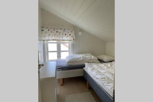 um pequeno quarto com uma cama e uma janela em Nordlandshus ved havet på Reine, Lofoten em Reine