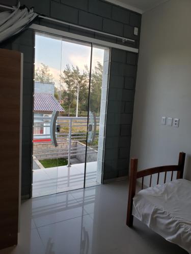 - une chambre avec un lit et une grande porte en verre dans l'établissement Residencial Soulmar Balneário Gaivota - SC -S02- Village Dunas Norte - 1,5 quadra do mar, à Balneário Gaivotas