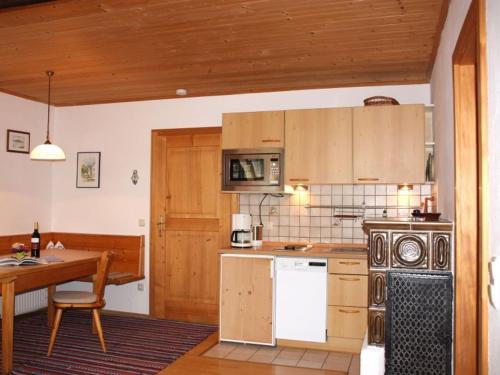 eine Küche mit Holzschränken, einem Tisch und einem Herd in der Unterkunft Jaklhof in Frasdorf