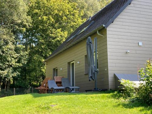 a house with a chair and an umbrella next to it at Au Bois de Rosée in Florennes