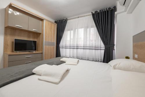 a bedroom with a large white bed and a television at Luxury Ultracentral in Piteşti