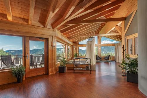 a living room with a wooden ceiling and windows at Almwelt Austria in Schladming