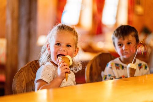 two children sitting at a table eating a banana at Almwelt Austria in Schladming