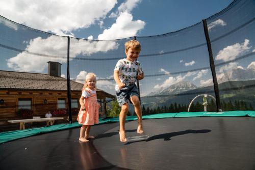 a boy and a girl playing on a trampoline at Almwelt Austria in Schladming