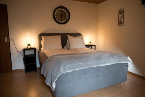 1 dormitorio con 1 cama grande, 2 mesas y reloj en La Légende, en Les Bois