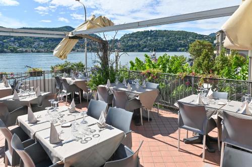a restaurant with tables and chairs and a view of the water at Hotel Marco's in Como