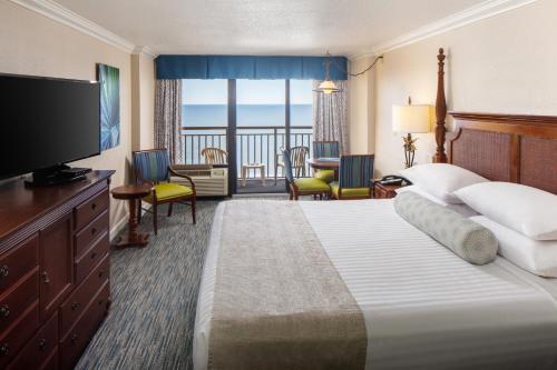 Cette chambre comprend un grand lit et une télévision. dans l'établissement Holiday Pavilion Resort on the Boardwalk, à Myrtle Beach