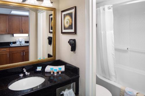 a bathroom with a sink and a mirror and a tub at Holiday Pavilion Resort on the Boardwalk in Myrtle Beach