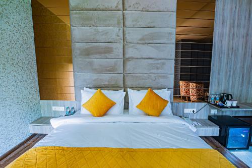 a bedroom with a large bed with yellow pillows at Regenta Inn Sambalpur, Farm Road in Sambalpur