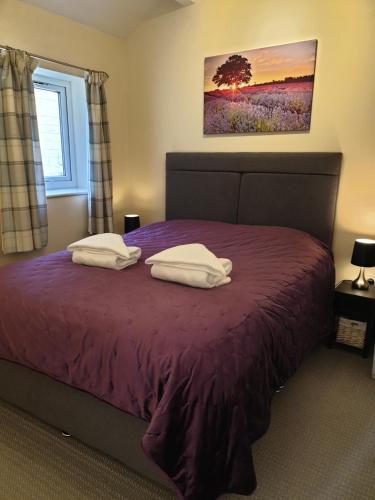 a bedroom with a purple bed with two pillows on it at Plover Cottage in Huddersfield