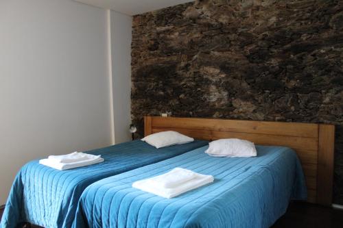 a bedroom with a blue bed with towels on it at Quinta dos Castanheiros - Turismo Rural in Negreda