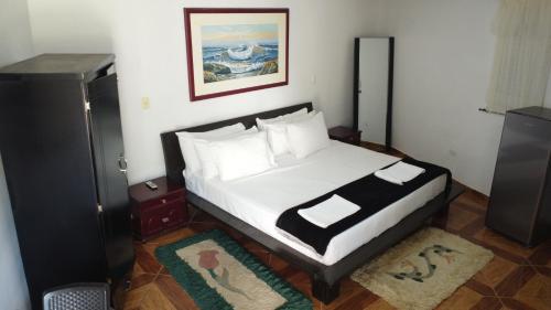 a bedroom with a bed with white sheets and pillows at Eco-Hotel Villa Elina in Ríohacha