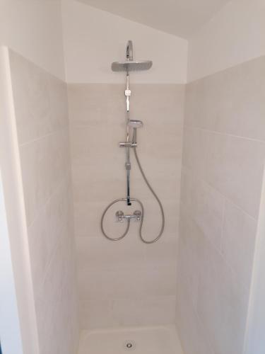 a shower in a white tiled bathroom with a pipe at L'atelier de Guytou et Spa in Cheval-Blanc