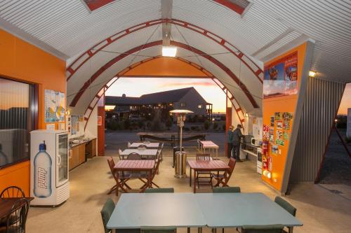 a restaurant with tables and chairs in a building at Haast River Motels & Holiday Park in Haast