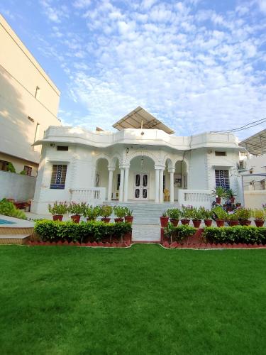 a large white house with a lawn in front of it at Homestay at Bungalow 97 Ajmer in Ajmer