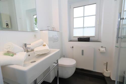 uma casa de banho branca com um lavatório e um WC em Spieker em Wenningstedt