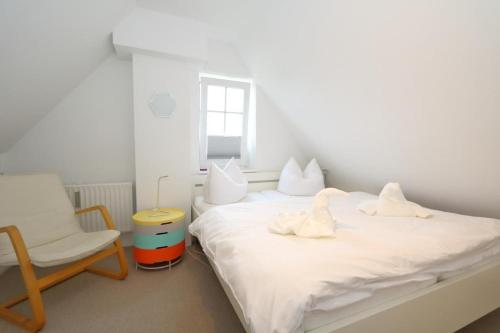 um quarto com dois cisnes numa cama e uma cadeira em Spieker em Wenningstedt