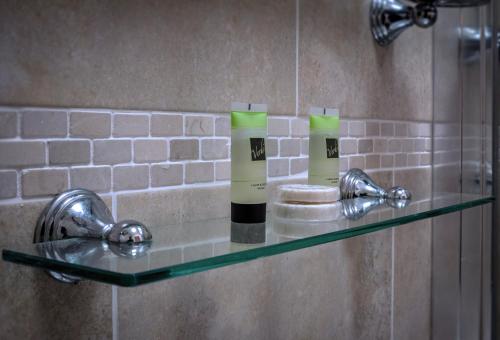 a glass shelf in a shower with two bottles on it at The Crown Hotel in Hailsham