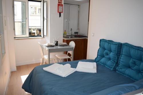 een kamer met een blauw bed, een tafel en een keuken bij Studio Station 1 in Coimbra