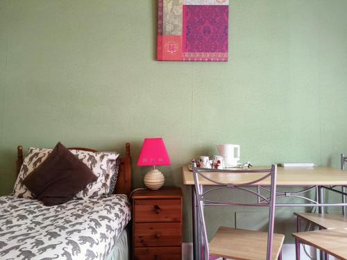 a bedroom with a bed and a desk with a pink lamp at aabAlree Guest House in Dundee